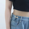 A close-up of a denim skirt featuring a gold star brooch belt buckle and a visible jean pocket.