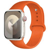 An Apple Watch in a silver case is shown attached to an orange silicone sport band.