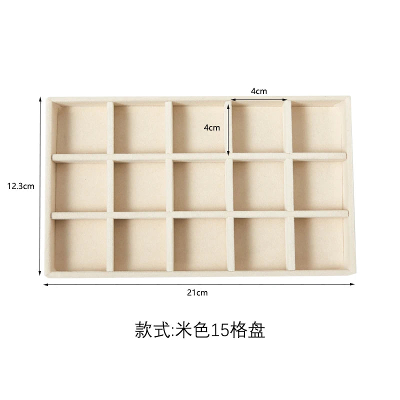 A light beige velvet jewelry organizer tray with 15 compartments.