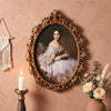 An ornate gold-framed oil painting featuring a portrait of a woman in white lace and flowing fabric.