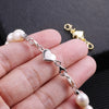 A hand holds a silver heart-shaped magnetic clasp for necklaces and bracelets alongside pearl beads.