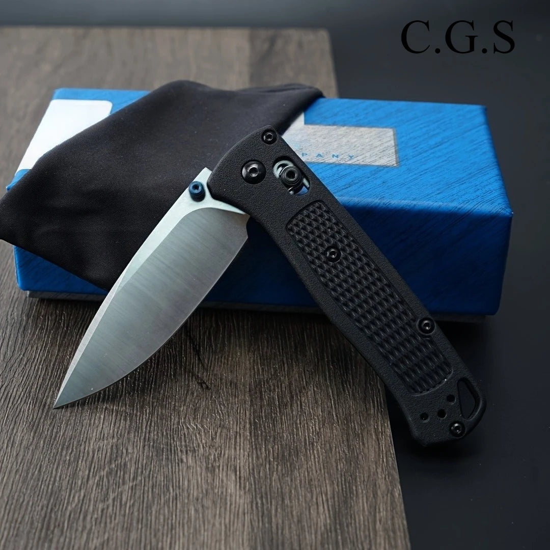 A black ultralight EDC folding knife with a drop point blade is shown resting on a blue box.