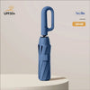 A navy blue automatic folding umbrella is shown standing upright on a light-colored surface.