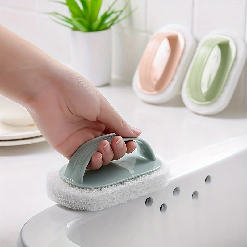 A hand is holding a green magic sponge scrubber with a long handle over a white sink.