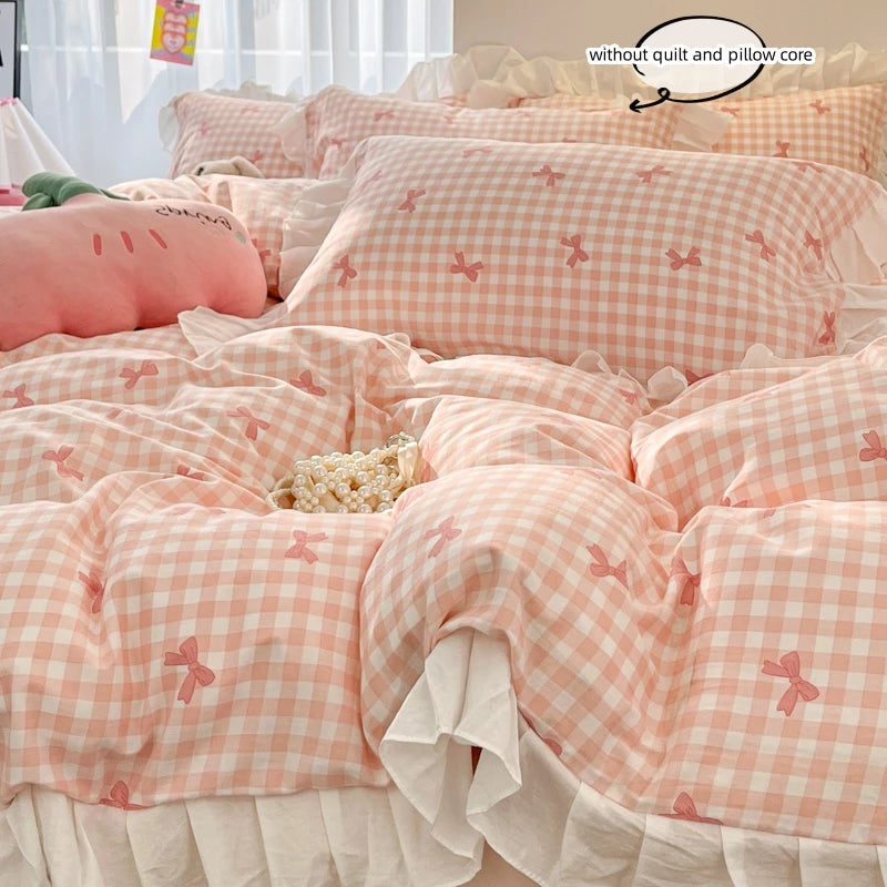 A set of three pink and white checkered ruffled bedding pieces including a duvet cover, pillow covers, and a sheet.