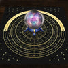 A dark cloth featuring a zodiac wheel with constellations and planets, centered by a glowing celestial sphere.