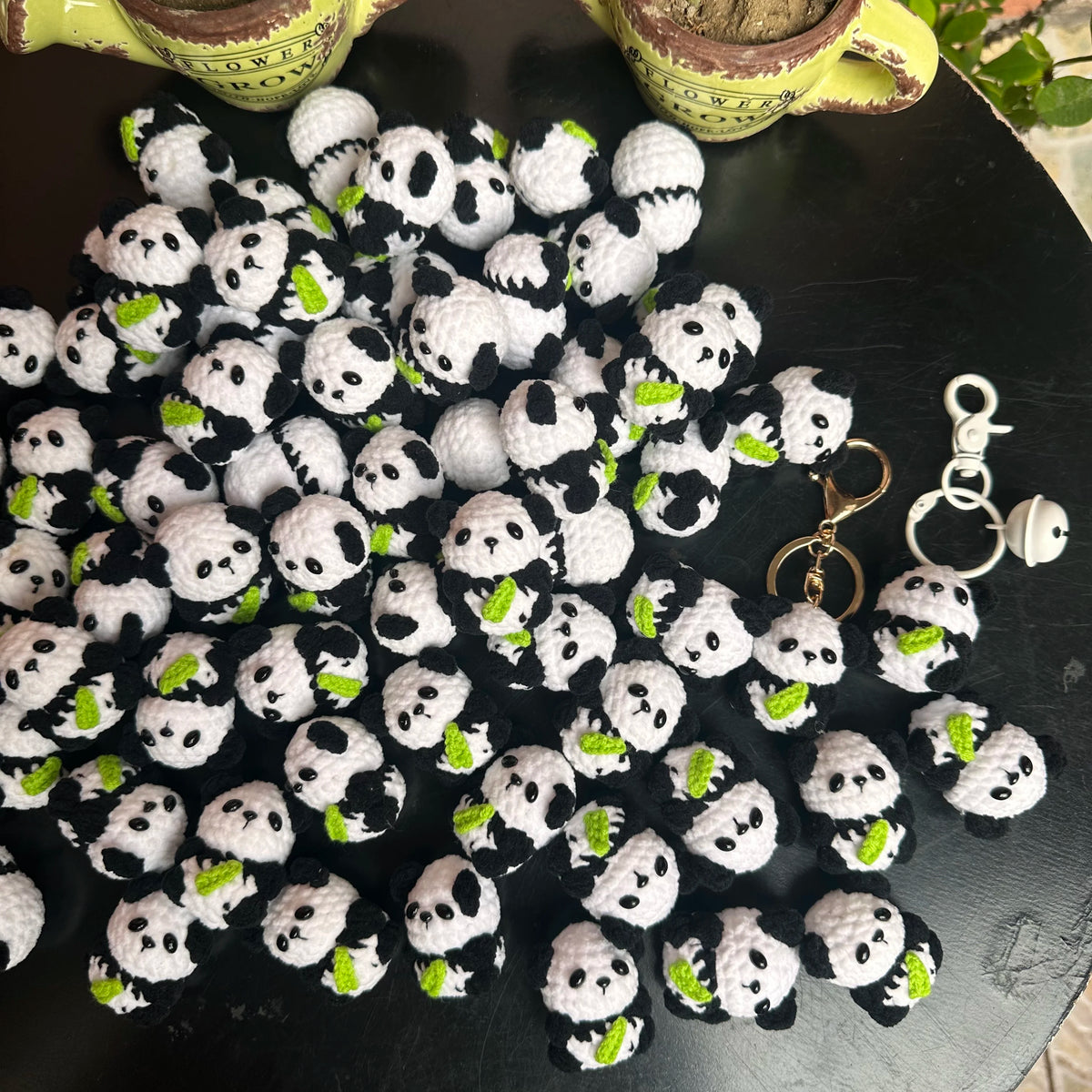 A pile of handmade crochet kitten keychains featuring cute panda and cartoon animal designs.