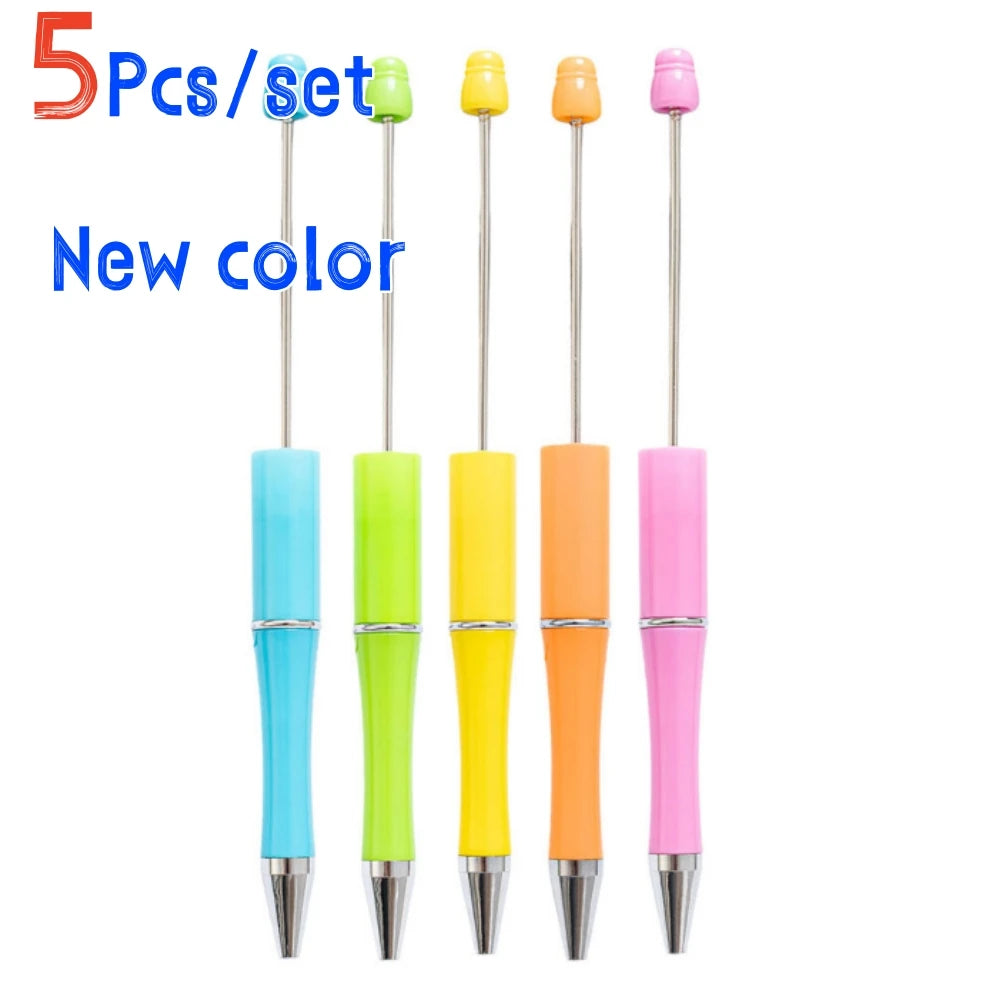 Un set de cinco bolígrafos de punta de tinta decorativos y de cuentas de colores: verde lima, amarillo, naranja y rosa.