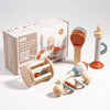 A box of wooden musical instrument toy showing various wooden instruments like a rattle and a small wooden bell.