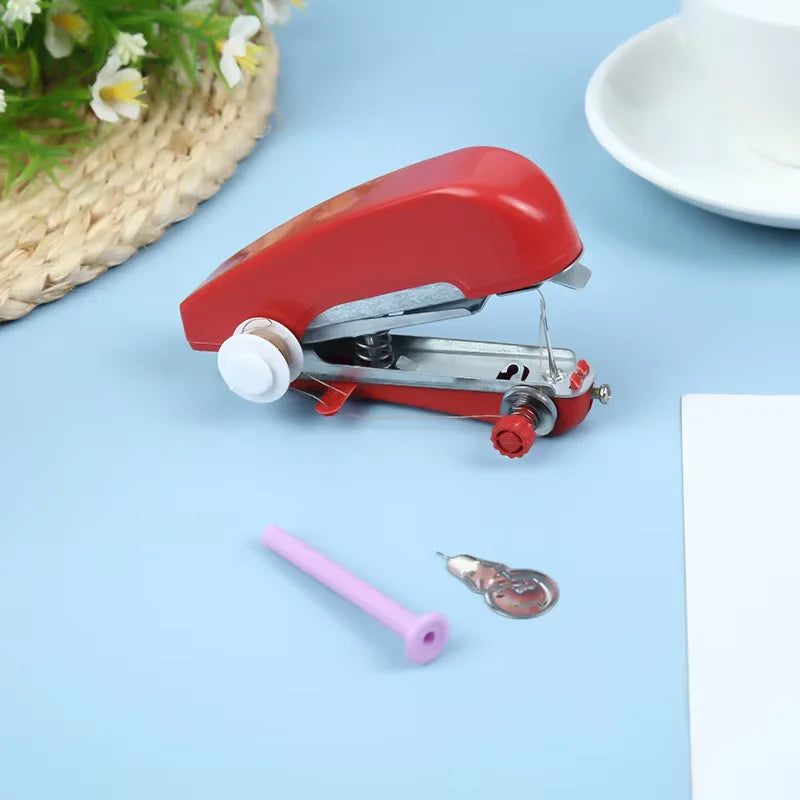 A red portable handheld sewing machine is shown on a light blue surface next to a pink needle and thread.