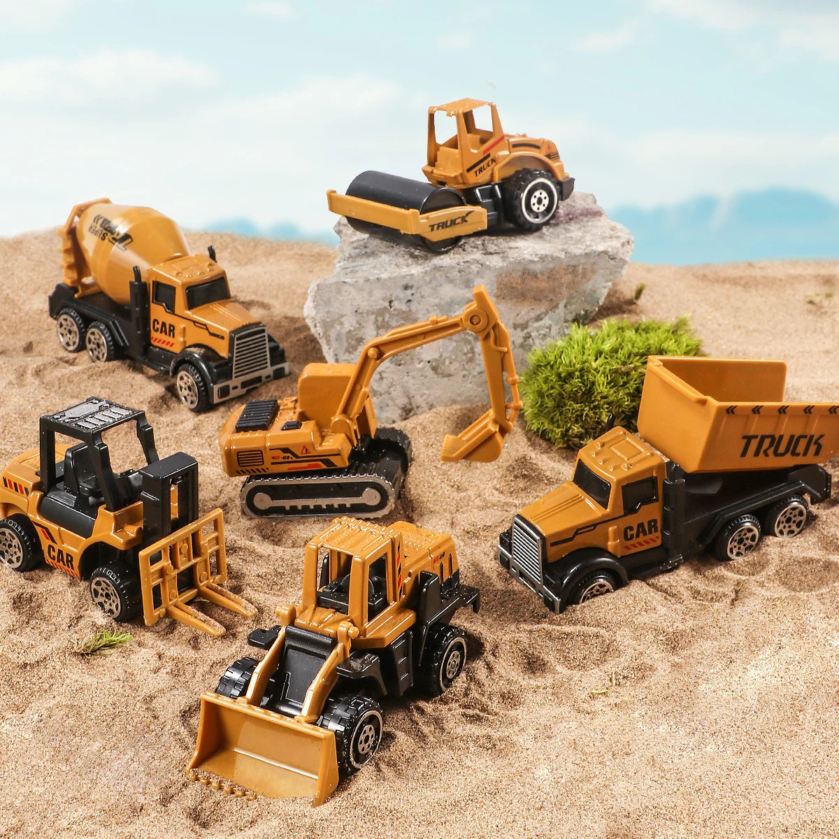 A set of diecast alloy construction vehicles including a yellow truck, excavator, and tractor toy on sand.