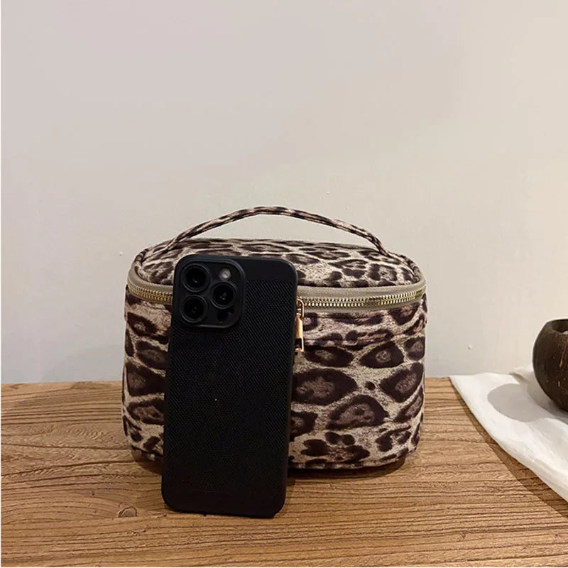 A black smartphone is placed on top of a leopard print cosmetic bag.