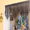 Black gothic lace curtain valance with irregular pendant trim hanging over a window.