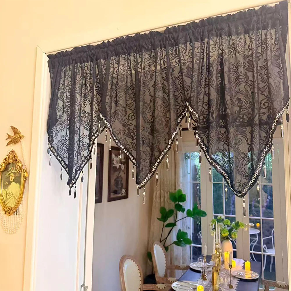 Black gothic lace curtain valance with irregular pendant trim hanging over a window.