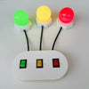 A white board with three colored light bulbs—green, yellow, and red—connected by wires.
