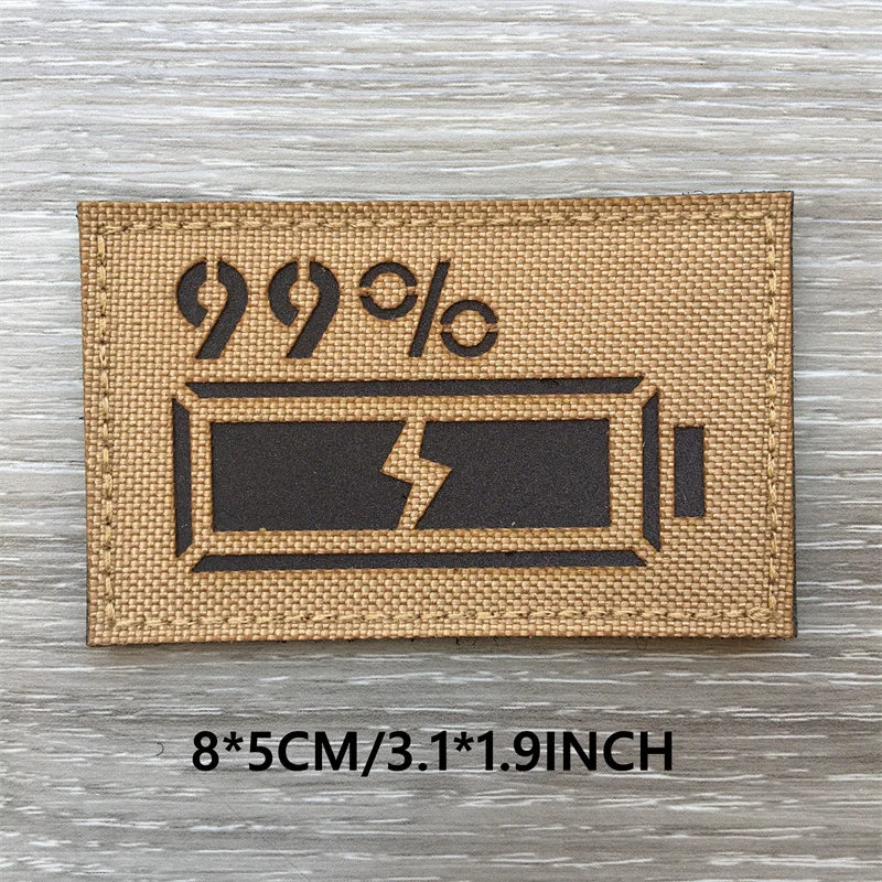 A rectangular tan tactical patch featuring a black lightning bolt symbol and 99% text on a wooden surface.
