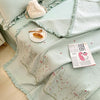 Light mint green quilted bedspread set with embroidered floral patterns and a fluffy cream pillow.