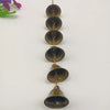 A vertical arrangement of vintage iron wind chimes with brass chains and dark bronze bells.