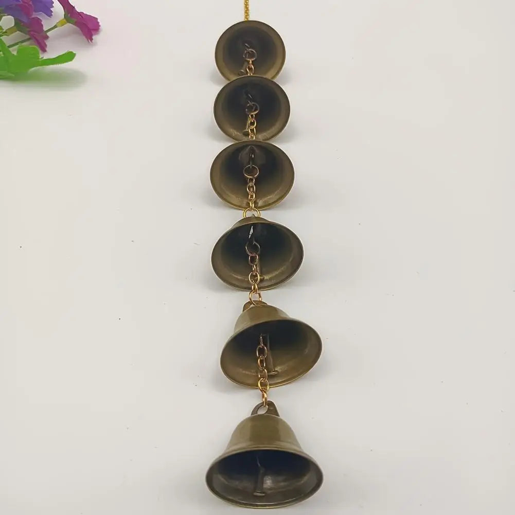 A vertical arrangement of vintage iron wind chimes with brass chains and dark bronze bells.