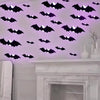 Wall décor featuring purple glowing bat silhouettes on a white wall above a marble mantelpiece.