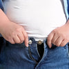 Hands inserting an adjustable metal button extender into the waistband of blue jeans.