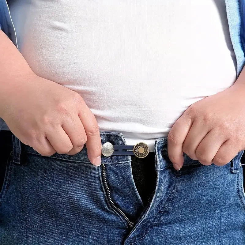 Hands inserting an adjustable metal button extender into the waistband of blue jeans.