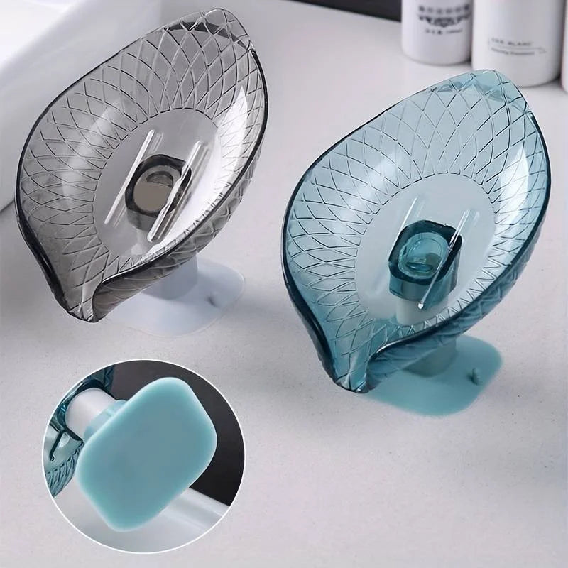A clear glass soap dish with a leaf design and suction cup is shown next to its blue soap.
