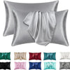 Un juego de fundas de almohada de seda satinada en varios tonos, incluyendo plata, gris, verde, rosa y azul.