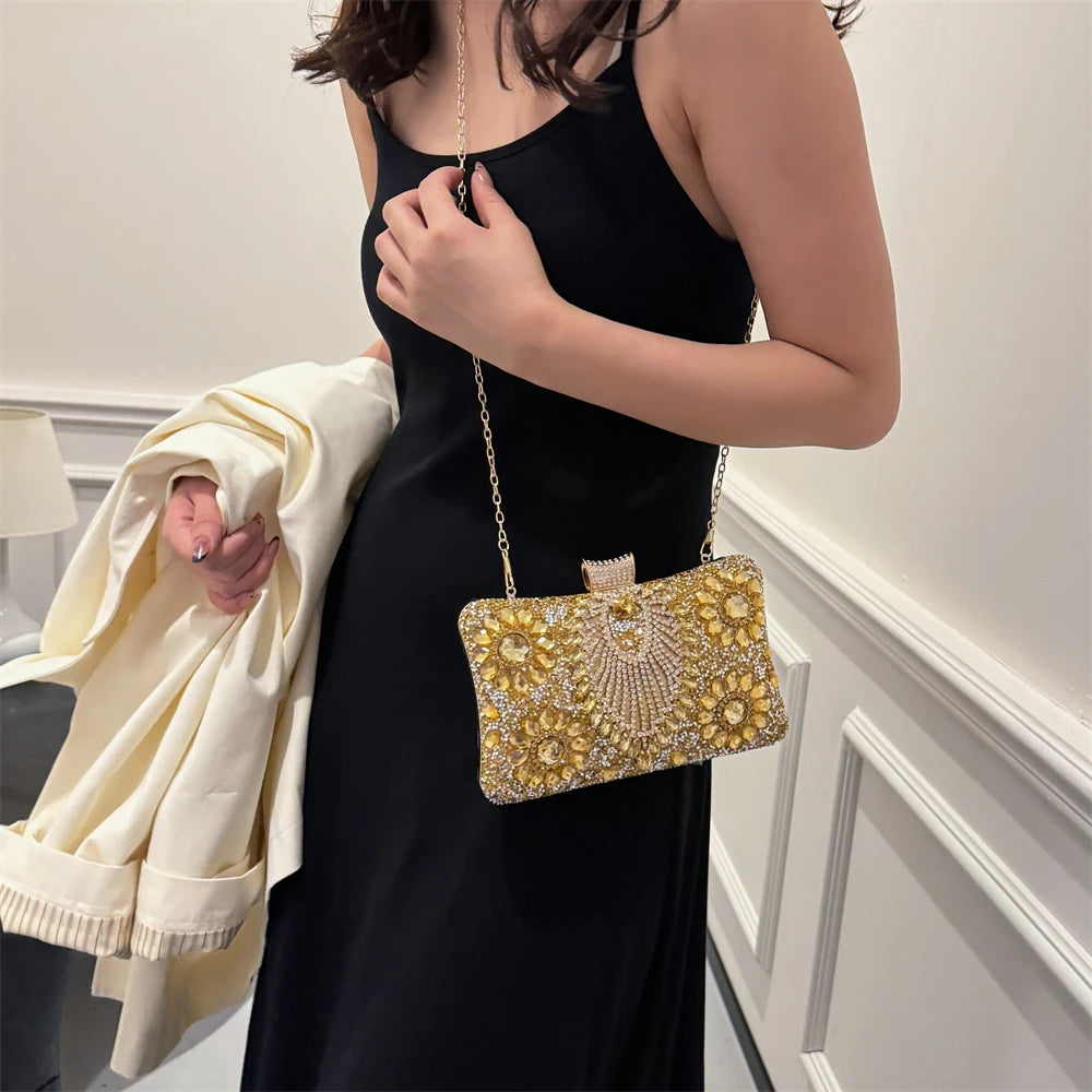 A woman wearing a black dress holds a gold rhinestone evening clutch with a chain strap.