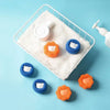 White laundry balls and a bottle are displayed on a white mesh tray against a light blue background.