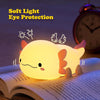 A glowing, cute axolotl night light rests on an open book.