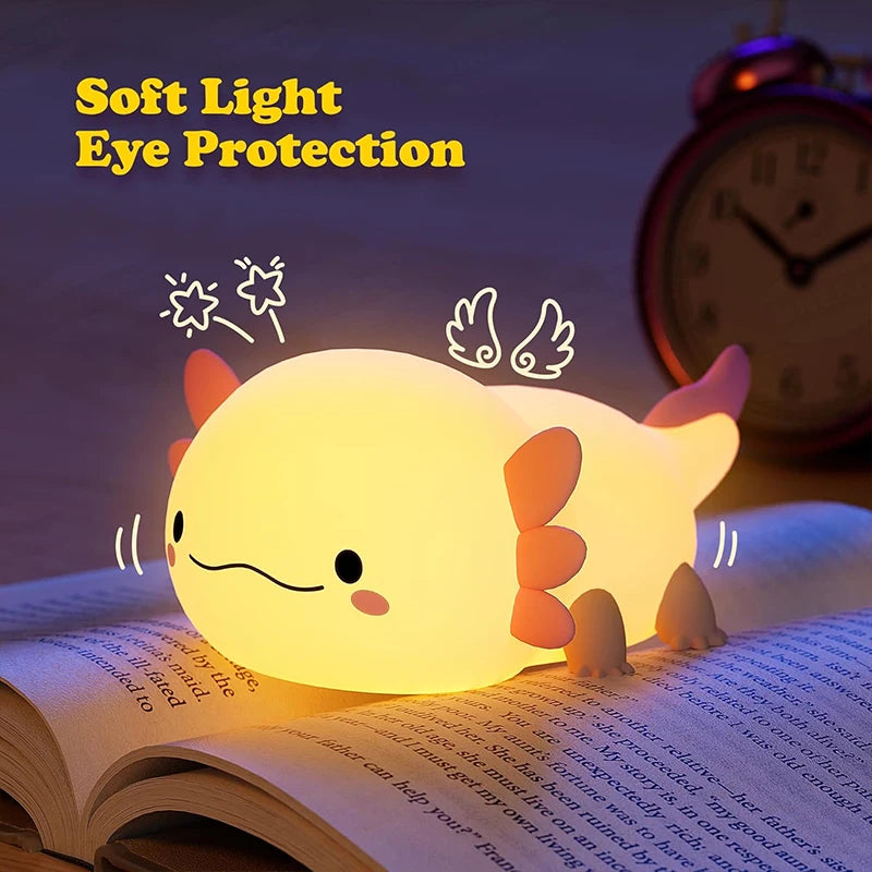 A glowing, cute axolotl night light rests on an open book.
