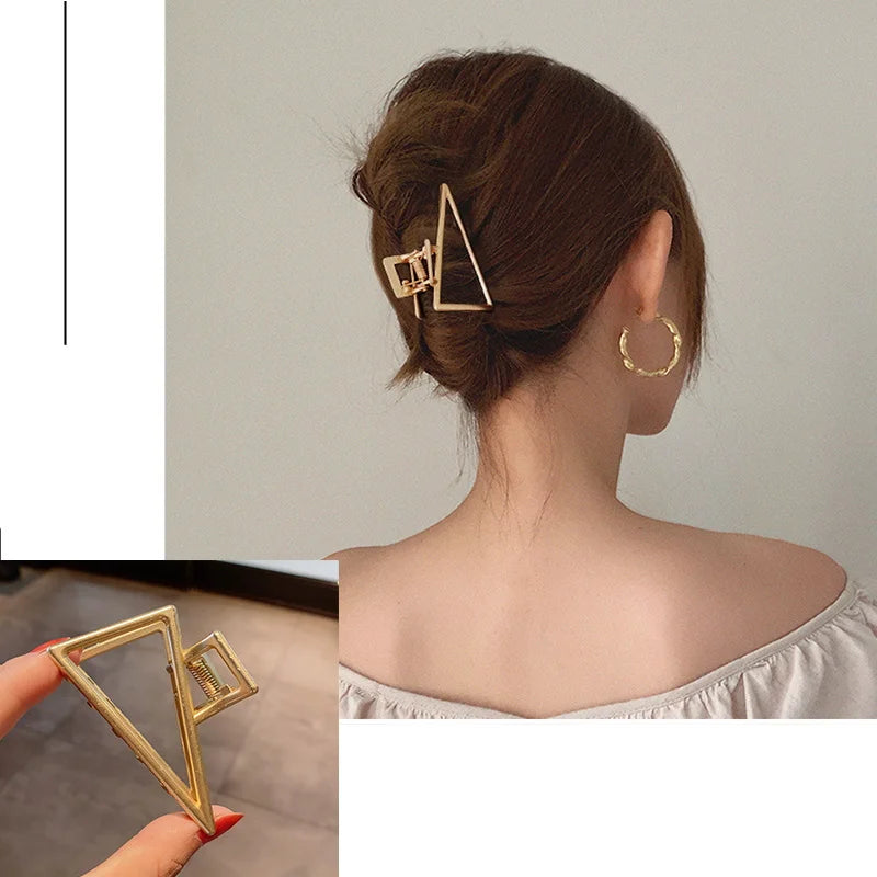 Nahaufnahme einer goldfarbenen geometrischen Dreieck-Haarspange in einer Hochsteckfrisur vor hellem Hintergrund.