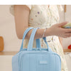 A light blue quilted insulated lunch tote bag being held by a woman in a white floral dress.