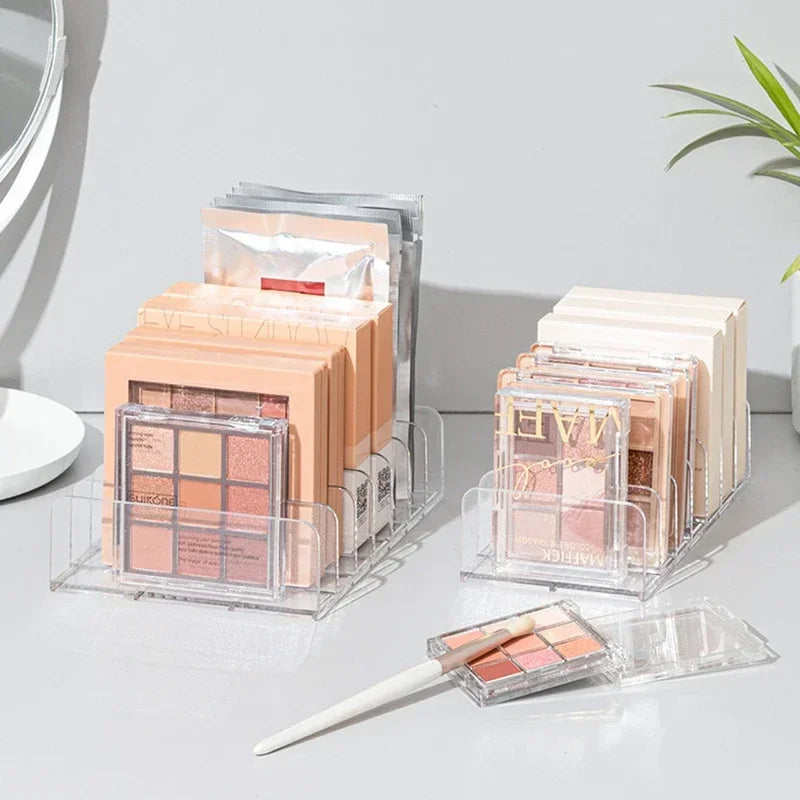 Klarer Plastikorganizer mit verschiedenen Make-up-Produkten und Paletten auf weißem Untergrund.