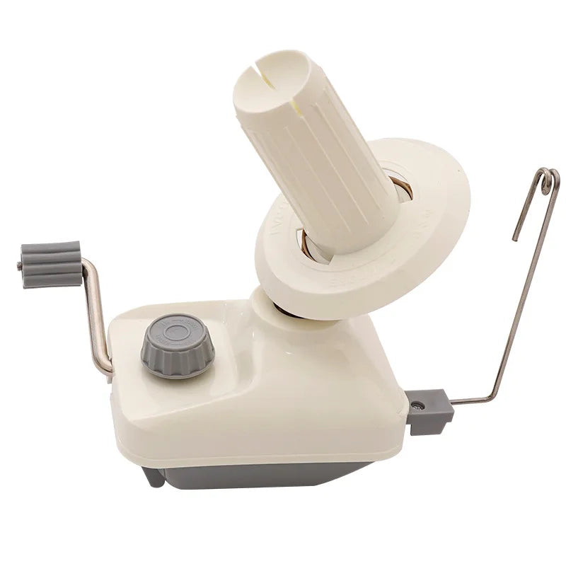 A compact hand-operated yarn ball winder with a white cylindrical spindle and a light beige base.