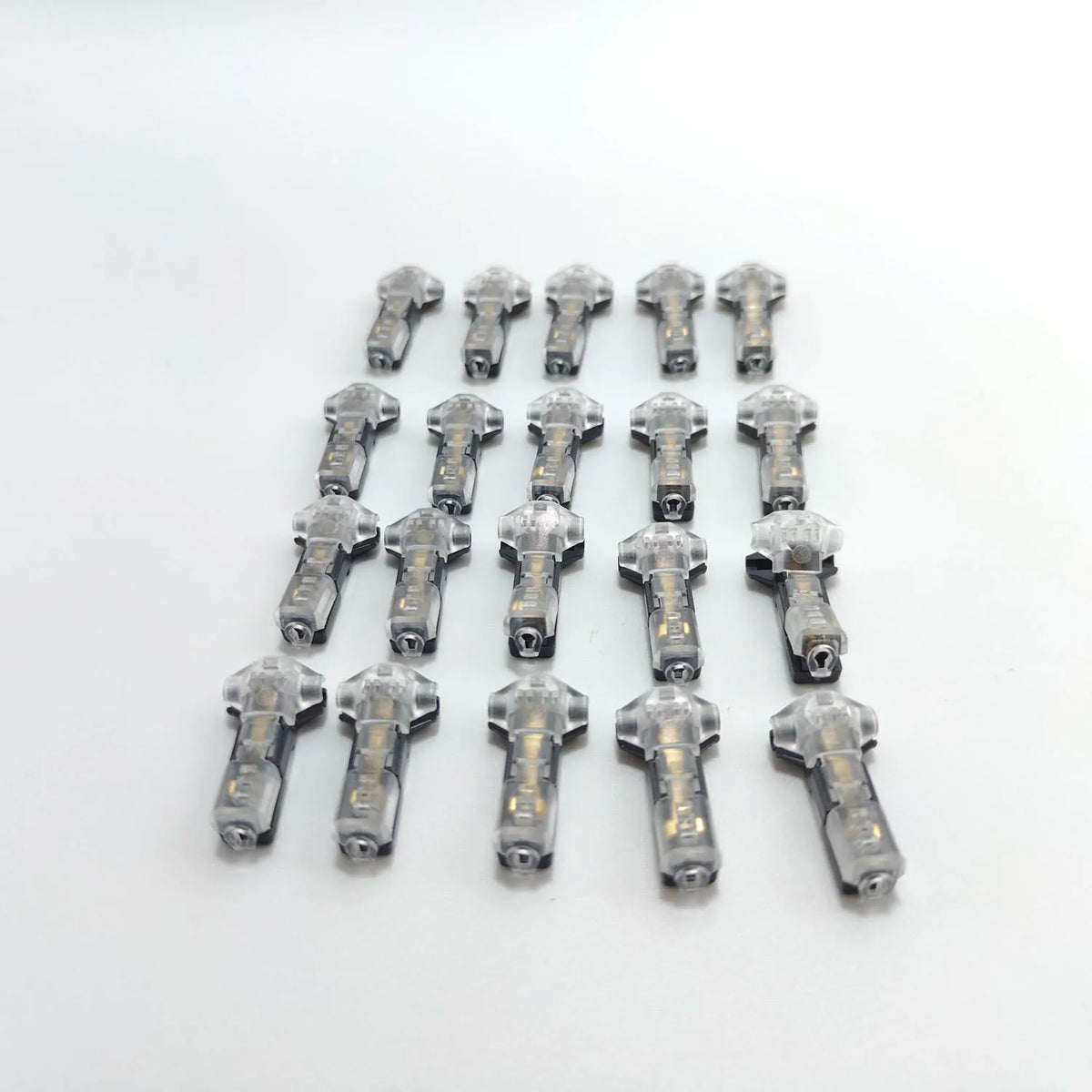 A collection of small, silver-colored quick solderless wire tap connectors arranged in a row.