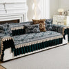 A dark teal and gold patterned sofa cover with quilted protection displayed on a white sofa.