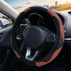 Close-up view of a steering wheel with a brown leather cover and black grip on a car interior.