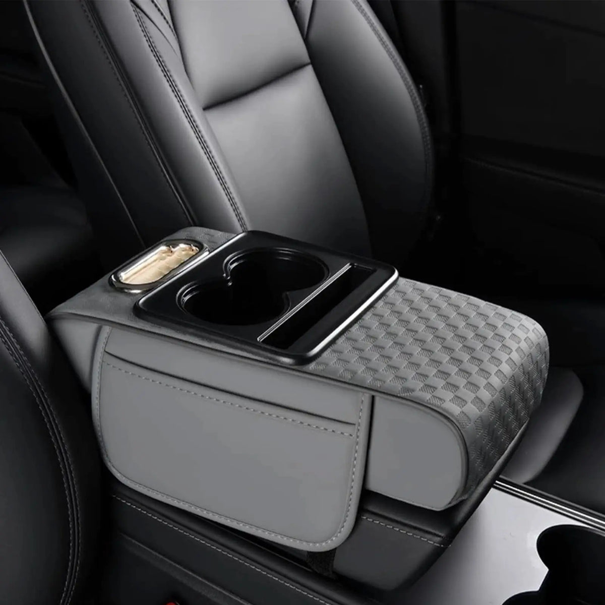 A gray car armrest cushion with integrated cupholders and storage compartments is shown in a dark vehicle interior.