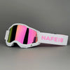 White professional MX off-road goggles with a vibrant iridescent lens and a pink strap labeled NAFE18