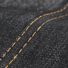 Close-up of dark denim fabric showing a visible orange stitching line on the material.