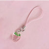A pink strawberry resin charm attached to a silver keychain with a pink cord.