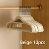 Beige velvet non-slip hangers hanging on a wooden rod in a closet