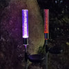A vertical glass tube light with a purple glow and an orange glow mounted on a pole.