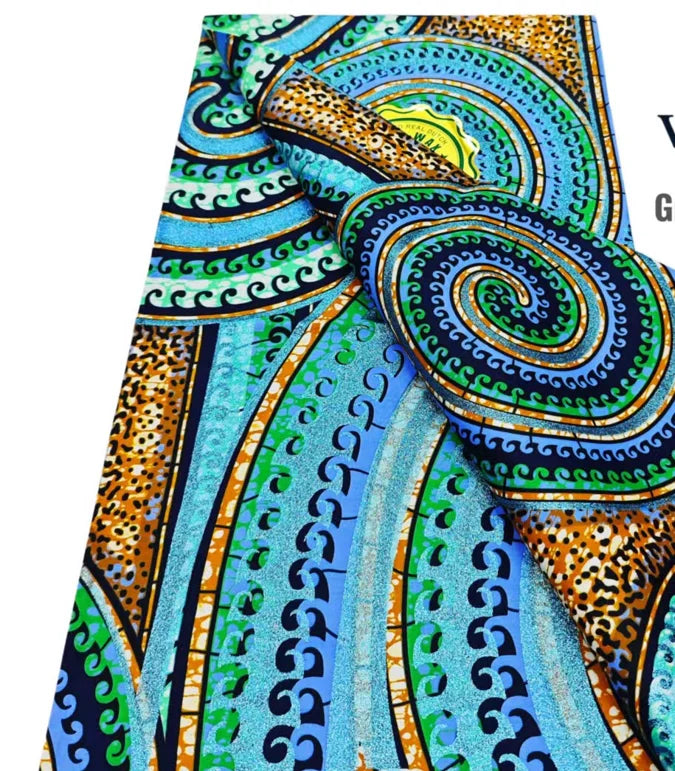 Close-up of pink glitter African wax print fabric featuring swirling patterns in teal, green, and orange tones.