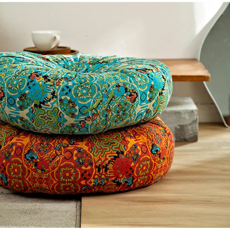 A vibrant orange and blue bohemian cotton linen floor cushion with a patterned fabric resting on a wooden surface.