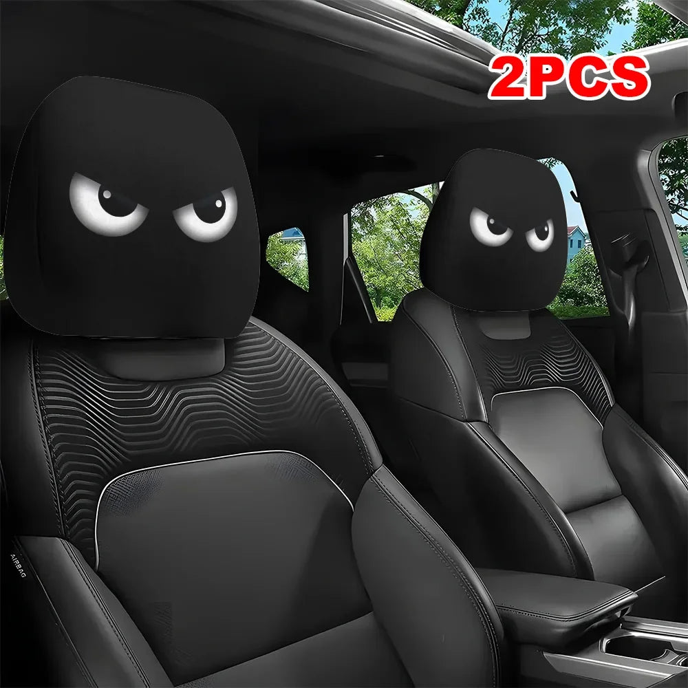 A pair of black car headrest covers with slanted eyes are shown inside a vehicle interior.