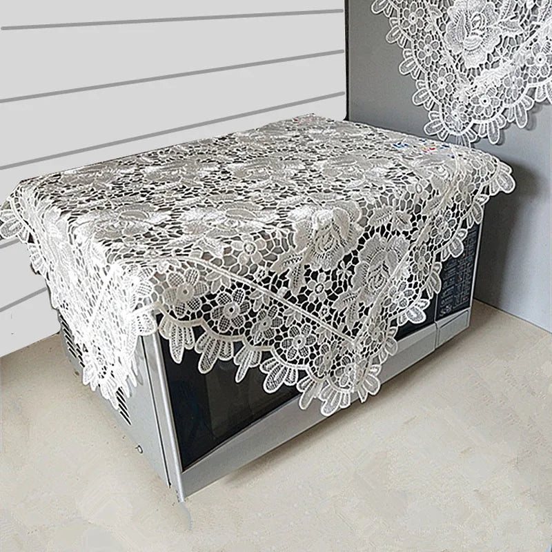 A silver lace tablecloth with an embroidered rose design is displayed on a table.