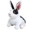 A white and black plush rabbit with pink inner ears is shown in a sitting pose.